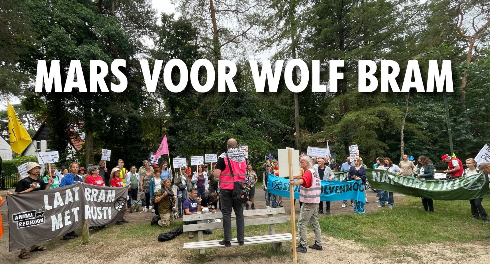 Foto van activisten in het bos van Maarn. Met daarop de tekst: 'Mars voor wolf Bram'